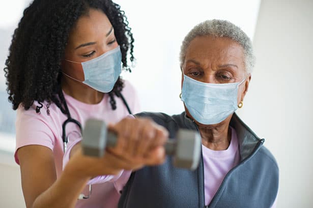 Nurse Helping Elderly Woman with Dumbbell Exercise