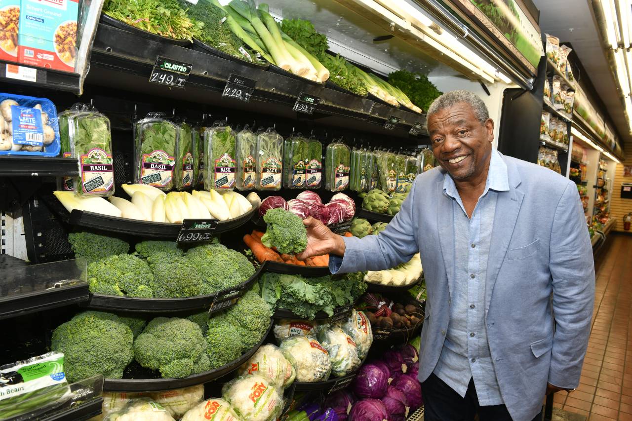 Hombre visto de frente en una tienda de alimentos que sonríe mientras compra productos agrícolas