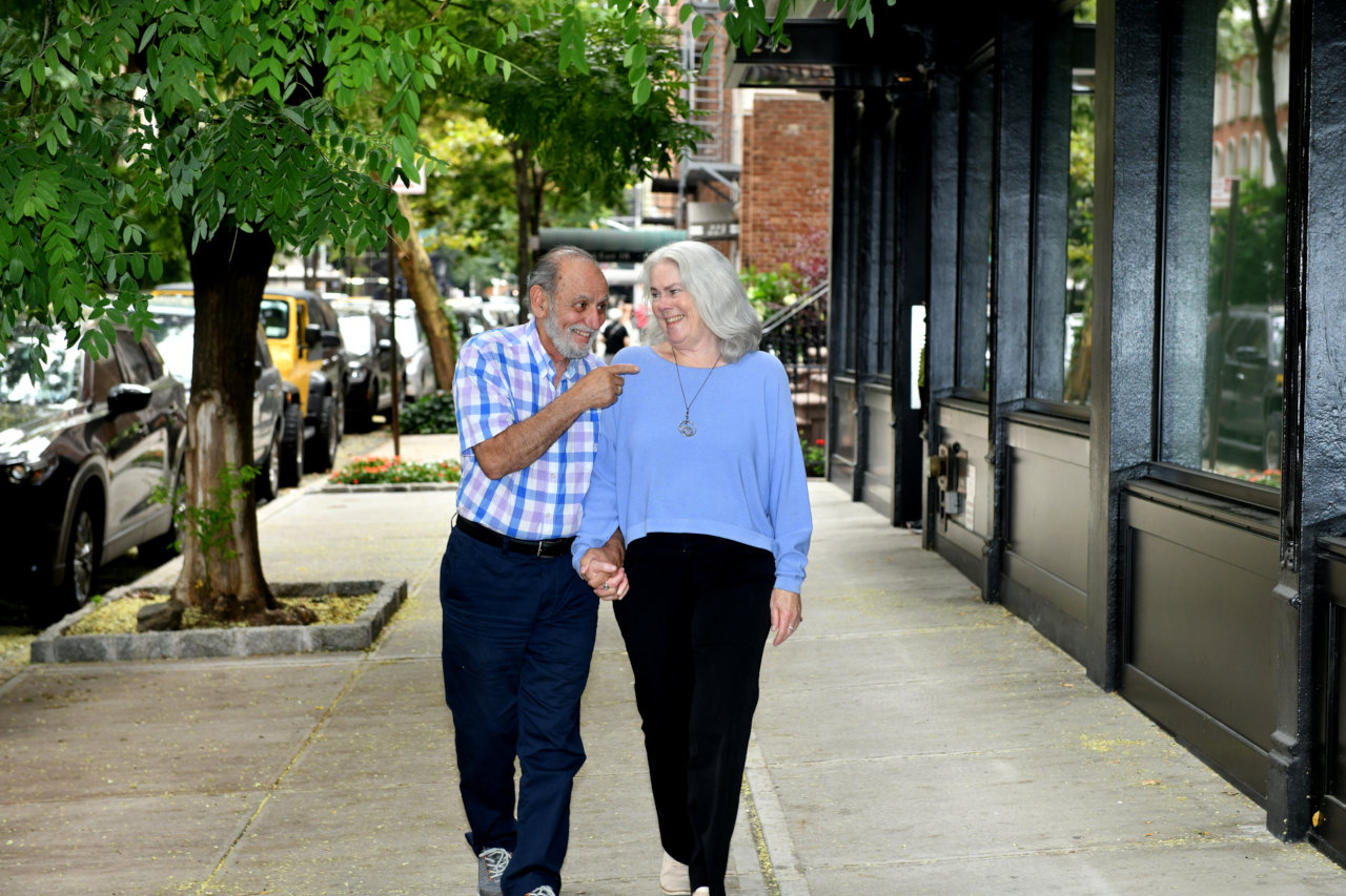A resident couple hold hands as they walk down the sidewalk.