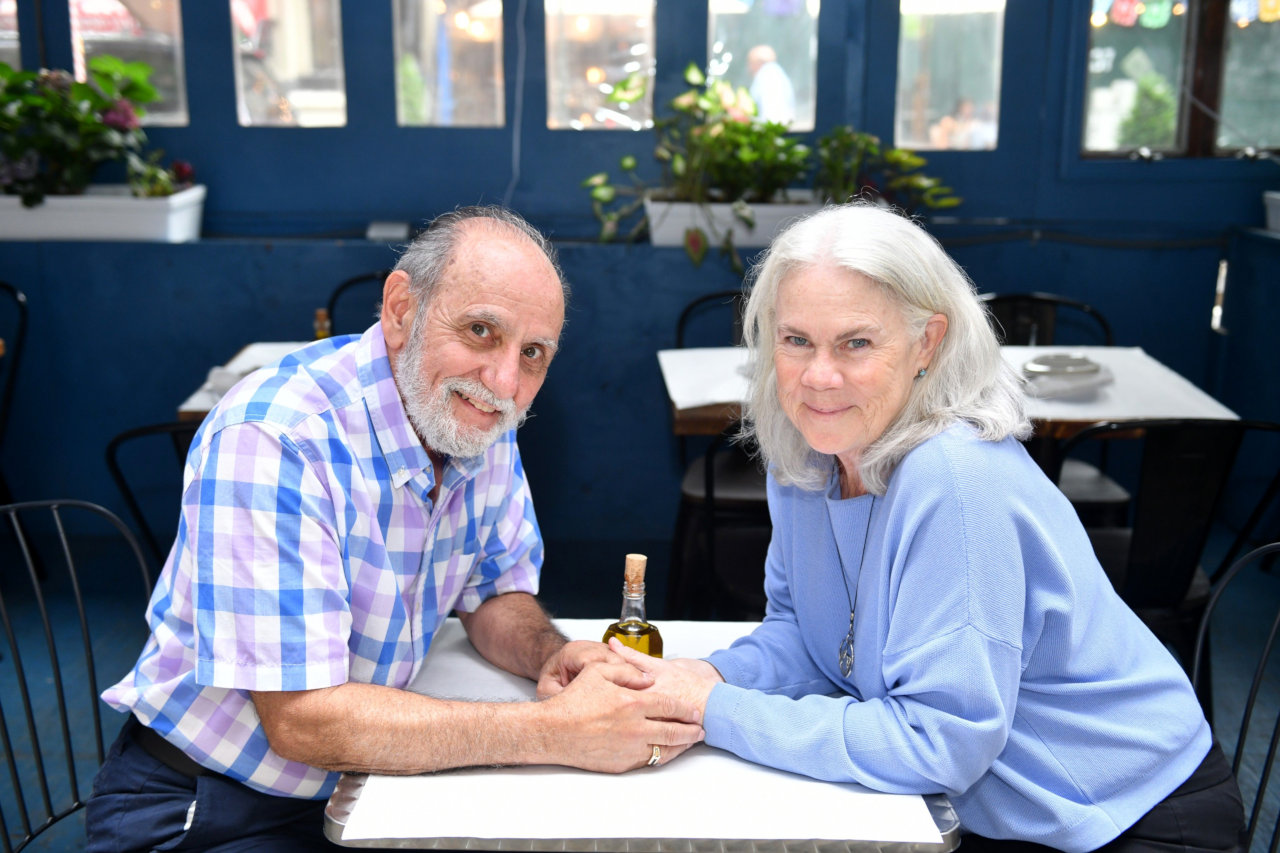 Beneficiaries An elderly couple hold hands at a restaurant.